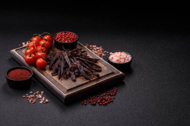 Kurutulmuş at eti ya da koyu beton arka planda tuz ve baharatlı biftek dilimleri.