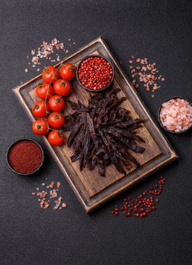 Kurutulmuş at eti ya da koyu beton arka planda tuz ve baharatlı biftek dilimleri.