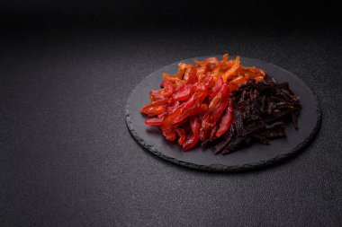 Kurutulmuş, tuzlu ve baharatlı tavuk dilimleri koyu beton arka planda.