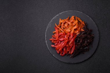 Kurutulmuş, tuzlu ve baharatlı tavuk dilimleri koyu beton arka planda.