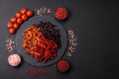 Kurutulmuş, tuzlu ve baharatlı tavuk dilimleri koyu beton arka planda.