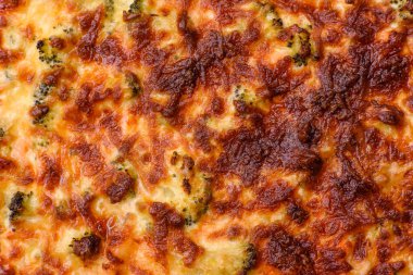 Brokolili, peynirli, baharatlı ve otlu lezzetli taze kiş koyu beton bir arka planda parçalara bölünmüş.