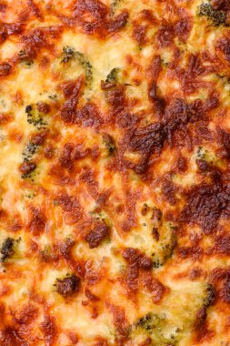 Brokolili, peynirli, baharatlı ve otlu lezzetli taze kiş koyu beton bir arka planda parçalara bölünmüş.