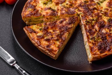 Brokolili, peynirli, baharatlı ve otlu lezzetli taze kiş koyu beton bir arka planda parçalara bölünmüş.