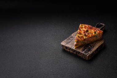 Brokolili, peynirli, baharatlı ve otlu lezzetli taze kiş koyu beton bir arka planda parçalara bölünmüş.