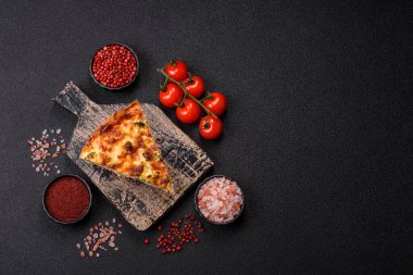 Brokolili, peynirli, baharatlı ve otlu lezzetli taze kiş koyu beton bir arka planda parçalara bölünmüş.