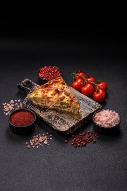 Brokolili, peynirli, baharatlı ve otlu lezzetli taze kiş koyu beton bir arka planda parçalara bölünmüş.