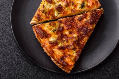 Brokolili, peynirli, baharatlı ve otlu lezzetli taze kiş koyu beton bir arka planda parçalara bölünmüş.