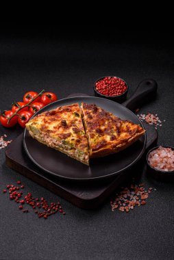 Brokolili, peynirli, baharatlı ve otlu lezzetli taze kiş koyu beton bir arka planda parçalara bölünmüş.