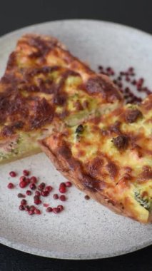 Brokolili, peynirli, baharatlı ve otlu lezzetli taze kiş koyu beton bir arka planda parçalara bölünmüş.