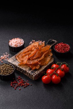 Kurutulmuş, tuzlu ve baharatlı kurutulmuş tavuk eti, koyu beton arka planda.