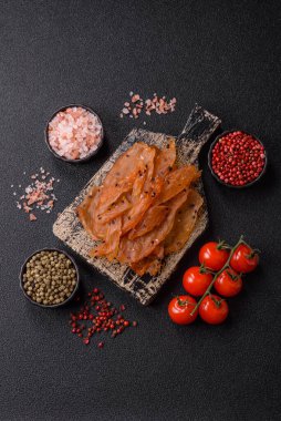 Kurutulmuş, tuzlu ve baharatlı kurutulmuş tavuk eti, koyu beton arka planda.
