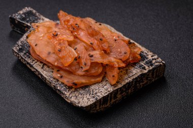 Kurutulmuş, tuzlu ve baharatlı kurutulmuş tavuk eti, koyu beton arka planda.