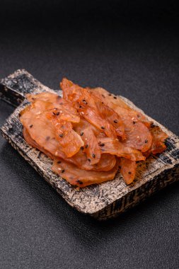 Kurutulmuş, tuzlu ve baharatlı kurutulmuş tavuk eti, koyu beton arka planda.