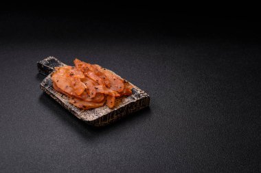 Kurutulmuş, tuzlu ve baharatlı kurutulmuş tavuk eti, koyu beton arka planda.