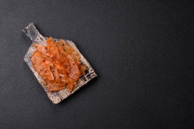 Kurutulmuş, tuzlu ve baharatlı kurutulmuş tavuk eti, koyu beton arka planda.