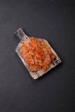 Kurutulmuş, tuzlu ve baharatlı kurutulmuş tavuk eti, koyu beton arka planda.