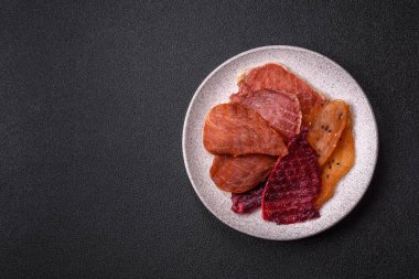 Kurutulmuş et, tuz ve baharatla birlikte koyu beton arka planda.