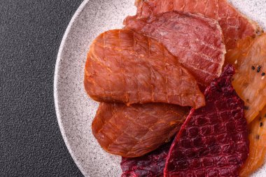 Kurutulmuş et, tuz ve baharatla birlikte koyu beton arka planda.