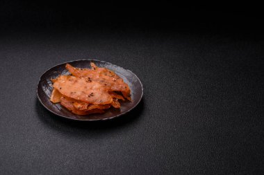 Kurutulmuş, tuzlu ve baharatlı kurutulmuş tavuk eti, koyu beton arka planda.