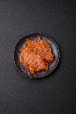 Kurutulmuş, tuzlu ve baharatlı kurutulmuş tavuk eti, koyu beton arka planda.