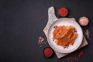 Kurutulmuş, tuzlu ve baharatlı kurutulmuş tavuk eti, koyu beton arka planda.