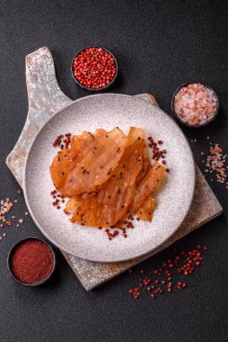 Kurutulmuş, tuzlu ve baharatlı kurutulmuş tavuk eti, koyu beton arka planda.