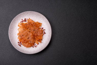 Kurutulmuş, tuzlu ve baharatlı kurutulmuş tavuk eti, koyu beton arka planda.