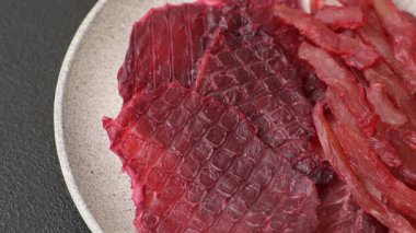 Kurutulmuş sığır eti dilimleri, kurutulmuş et, kiraz veya erik aromalı, tuz ve baharatlar koyu beton arka planda.