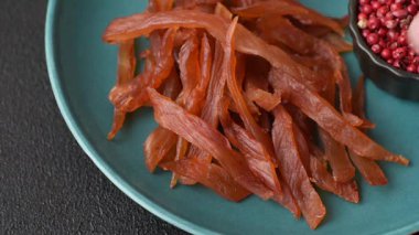 Kurutulmuş hindi eti, tuzlu ve baharatlı koyu beton arka planda.