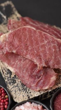 Kurutulmuş et, tuz ve baharatla birlikte koyu beton arka planda dilimler.