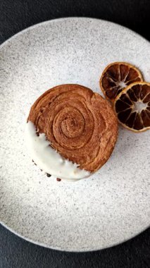 Yuvarlak, tatlı New York rulo kruvasanı. Koyu beton bir arka planda krema var.