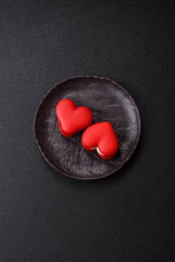 Kalp şeklinde kırmızı badem kurabiyeleri, Sevgililer Günü tatili için tatlılar koyu beton arka planda.