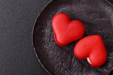 Kalp şeklinde kırmızı badem kurabiyeleri, Sevgililer Günü tatili için tatlılar koyu beton arka planda.