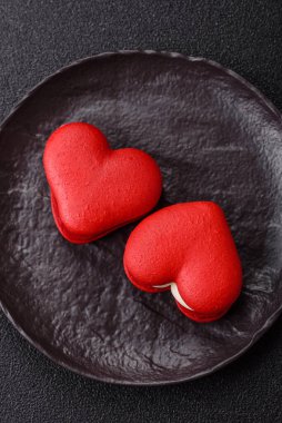 Kalp şeklinde kırmızı badem kurabiyeleri, Sevgililer Günü tatili için tatlılar koyu beton arka planda.
