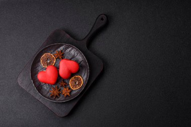 Kalp şeklinde kırmızı badem kurabiyeleri, Sevgililer Günü tatili için tatlılar koyu beton arka planda.