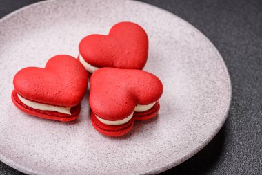 Kalp şeklinde kırmızı badem kurabiyeleri, Sevgililer Günü tatili için tatlılar koyu beton arka planda.