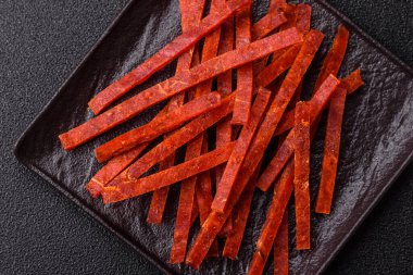 Koyu beton zeminde tuzlu ve baharatlı kurutulmuş balık çubukları.