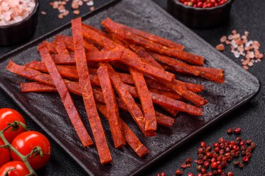 Koyu beton zeminde tuzlu ve baharatlı kurutulmuş balık çubukları.