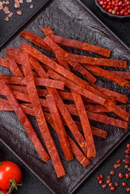 Koyu beton zeminde tuzlu ve baharatlı kurutulmuş balık çubukları.