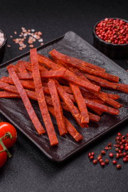 Koyu beton zeminde tuzlu ve baharatlı kurutulmuş balık çubukları.