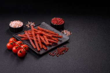 Koyu beton zeminde tuzlu ve baharatlı kurutulmuş balık çubukları.