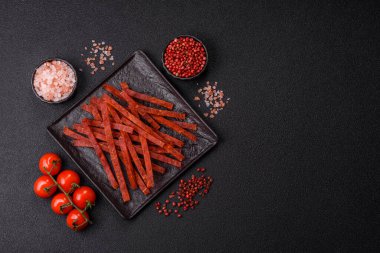 Koyu beton zeminde tuzlu ve baharatlı kurutulmuş balık çubukları.