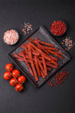 Koyu beton zeminde tuzlu ve baharatlı kurutulmuş balık çubukları.