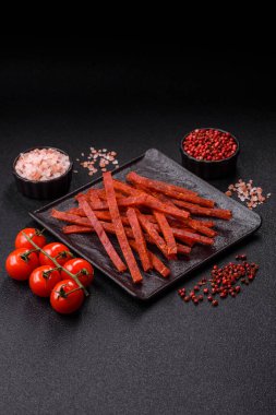 Koyu beton zeminde tuzlu ve baharatlı kurutulmuş balık çubukları.