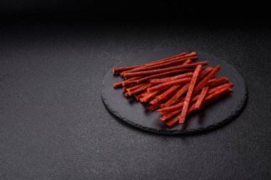 Koyu beton zeminde tuzlu ve baharatlı kurutulmuş balık çubukları.