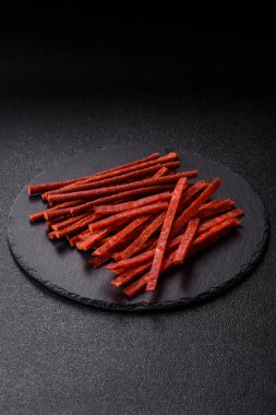 Koyu beton zeminde tuzlu ve baharatlı kurutulmuş balık çubukları.