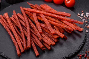 Koyu beton zeminde tuzlu ve baharatlı kurutulmuş balık çubukları.