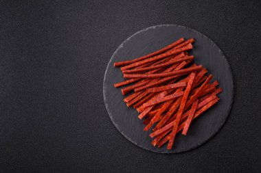 Koyu beton zeminde tuzlu ve baharatlı kurutulmuş balık çubukları.