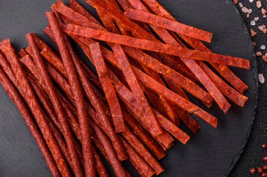 Koyu beton zeminde tuzlu ve baharatlı kurutulmuş balık çubukları.